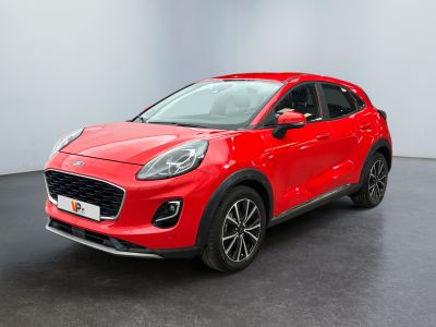 Une voiture rouge est garée dans une pièce au sol noir.