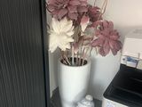 a white vase with flowers in it next to a black and white printer