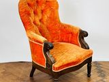 an orange chair sitting on top of a wooden floor next to a white wall