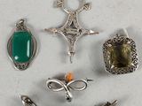 Plusieurs bijoux argentés et verts sont disposés sur une surface blanche