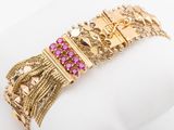 a close up of a gold bracelet with pink stones on it