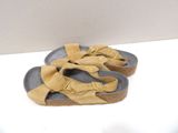 pair of tan sandals on a white surface with a white wall in the background