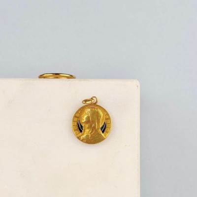 une pièce d'or sur laquelle est représenté un visage, posée sur une surface blanche