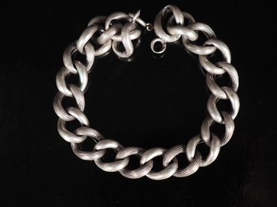 un gros plan d'un bracelet à chaîne argentée sur fond noir