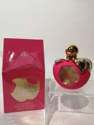 un flacon de parfum rose posé sur une table, à côté d'une boîte rose