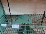 une cage métallique contenant une souris, posée sur une étagère