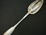 une vieille cuillère en argent à long manche posée sur une surface noire