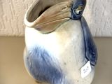 un vase bleu et blanc surmonté d'un oiseau
