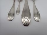 three silver spoons and a fork on a white surface