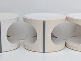 three white stools sitting next to each other on a white surface