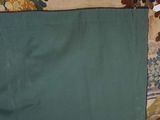 a green blanket on a floral couch with a tag on it