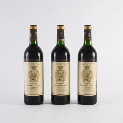trois bouteilles de vin posées les unes à côté des autres sur une surface blanche