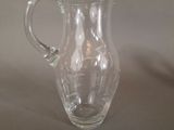 a clear glass pitcher with a handle on a table