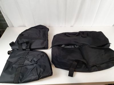 trois sacs noirs posés sur une table blanche, à côté d'un rideau