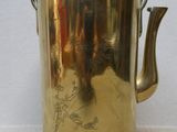 a brass tea pot with a handle on a white surface
