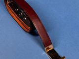 a brown leather keychain with a gold buckle on a blue background