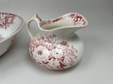 a red and white pitcher and a bowl on a table