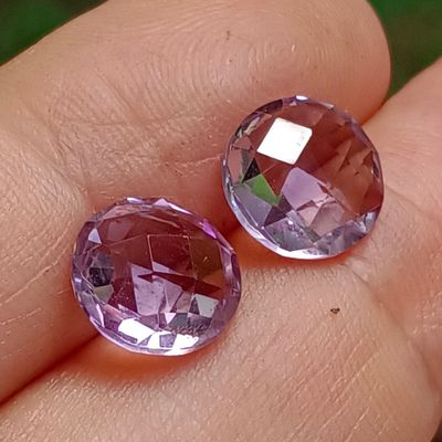 deux pierres précieuses violettes posées sur le doigt d'une personne