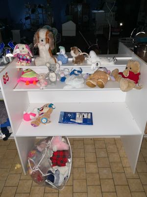 de nombreuses peluches posées sur une étagère blanche dans une pièce