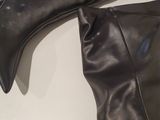 pair of black leather boots sitting on top of a white table