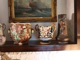 many vases sitting on a shelf with a painting in the background