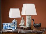 une table sur laquelle se trouvent une lampe, un vase, une assiette et un tableau