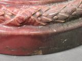 a close up of a red vase with a braid design on it