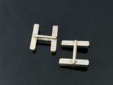 a pair of silver cufflinks on a black surface