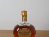 une bouteille de whisky posée sur une table en bois, avec un mur blanc en arrière-plan