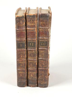 trois vieux livres posés l'un sur l'autre sur une surface blanche