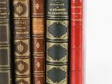 several old books are lined up in a row on a white surface