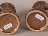 two brown vases with labels on them sitting on a table