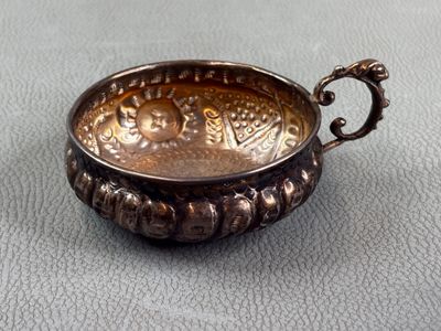 a silver bowl with a handle on a table