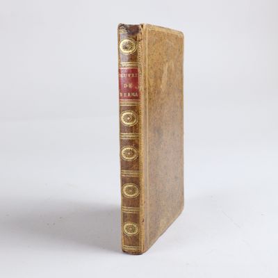 un livre marron à la couverture rouge posé sur une surface blanche
