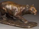 bronze statue of a tiger on a rock on a gray background