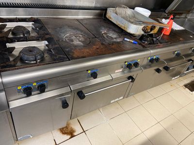 une plaque de cuisson sale dans une cuisine où sont posés des plats sales