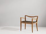une chaise en bois avec une assise noire dans une pièce blanche