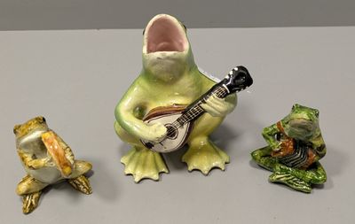 three figurines of frogs and a guitar on a table