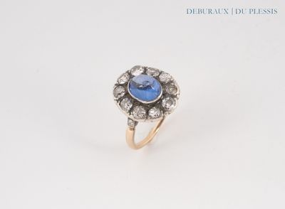 a close up of a ring with a blue stone surrounded by diamonds