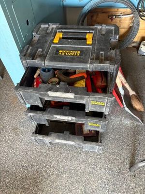 une boîte à outils contenant des outils, posée sur le sol