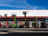 de nombreux engins de chantier de différents types garés devant un immeuble