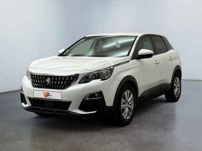 Une voiture blanche est garée dans une pièce au sol noir.