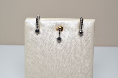 a pair of black and white diamond earrings sitting on top of a white purse