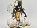 une image représentant la statue d'un homme tenant un panier rempli de verres à vin posé sur un socle