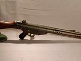 Un vieux pistolet est posé sur un socle, sur une surface blanche