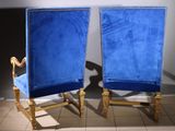 pair of blue velvet chairs in a room with a white wall
