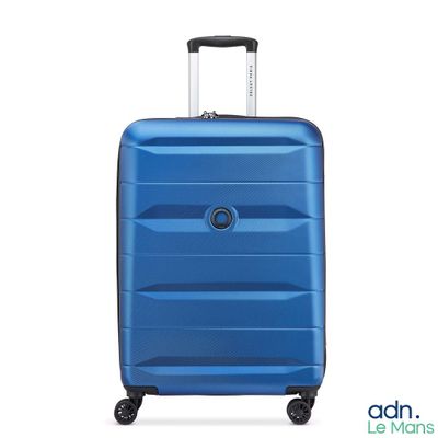 La valise bleue repose sur ses roulettes, posée sur une surface blanche.