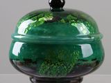 a green and black bowl with a lid on a table