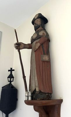 une statue représentant un homme tenant un bâton, placée dans un coin