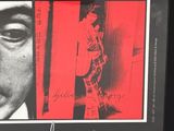 poster of a man in a suit and tie standing in front of a red background